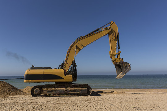 Máquina retroexcavadora trabajando en la playa.