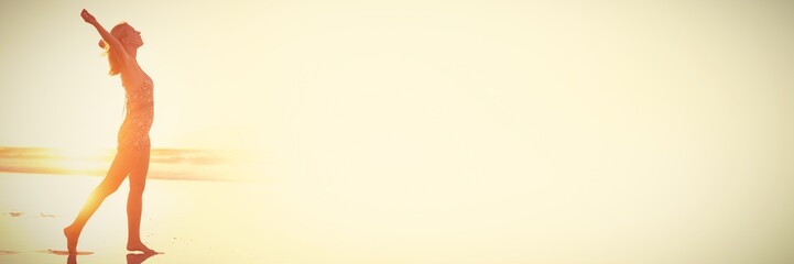 Side view of carefree woman with arms outstretched at beach