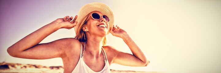 Happy woman wearing sunglasses and hat at beach