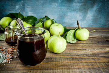 Home cooked dark salted classic caramel sauce, with green apples, wooden and dark blue background,