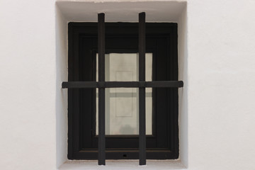 Dark window with black bars on white wall