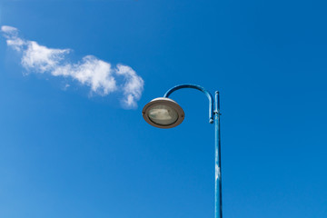 Blue lamppost with clouds under blue sky
