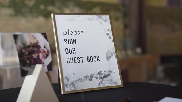 A sign at a wedding that reads "please sign our guest book" on a table