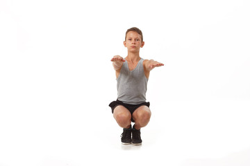 Teen in a T-shirt and shorts performs gymnastic exercises.