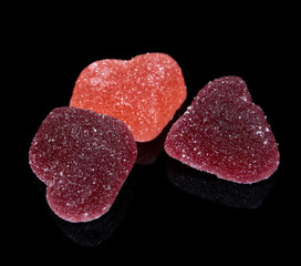 Pieces of marmalade in the shape of hearts isolated on a black background