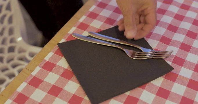 Cameriere sta apparecchiando la tovaglia a quadri rosso e bianco di un ristorante 