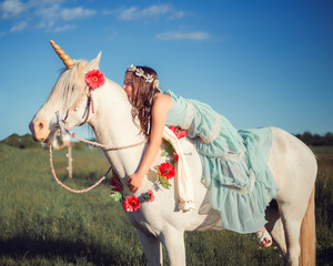 Girl with flower hair wreath sitting and leaning on white horse unicorn. Dreams come true © Yulia