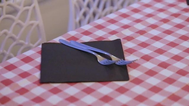 Cameriere sta apparecchiando la tovaglia a quadri rosso e bianco di un ristorante 