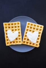 Delicious belgian waffles with cream on a black background