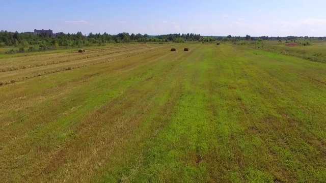 View from the flight over the fields with haystacks. Harvesting and mowing of grass for livestock feeding. 