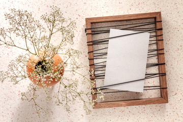 Unusual photo frame and white flowers in an orange vase on a dot table