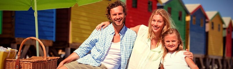 Fototapeta premium Portrait of fappy family sitting on blanket at beach
