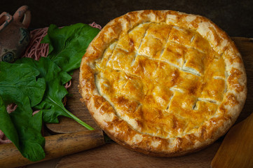 Vegetable pie homemade baking with spinach and onions, on a dark wooden background