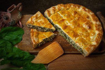 Vegetable pie homemade baking with spinach and onions, on a dark wooden background