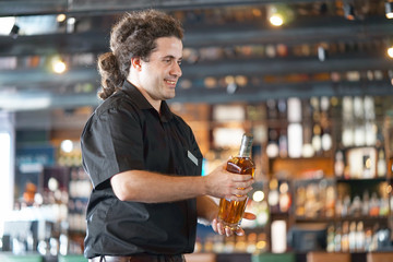 A barmaid men  carries a bottle of whiskey on a hand to the client of the hotel bar. The concept of service.