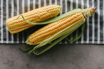 top view of fresh corn cobs on linen on concrete tabletop