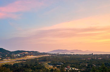 Colourful sunset over airport, mountains and forest on a tropical island      