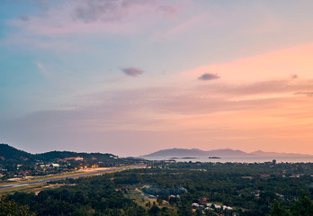 Colourful sunset over airport, mountains and forest on a tropical island      