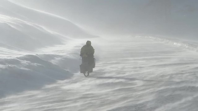Guy cycling upwind in snow storm