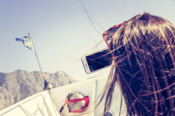 Touristin macht Selfie am Bug eines Passagierschiffes, Gardasee. Blauer Himmel und blaues Wasser.