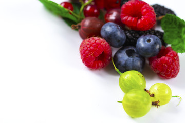 Close-up arrangement mixed, assorted berries including blackberries, strawberry, blueberry, raspberries and fresh leaf on white
