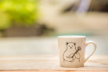 white mug on the wooden table outdoor and copy space.