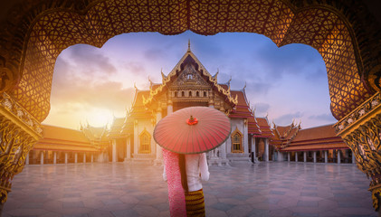 Woman with red umbrella at entrance of Marble Temple, Bangkok - obrazy, fototapety, plakaty