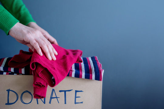 Donation Concept. Woman Droping her Used Old Clothes into a Donate Box