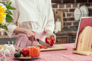 cropped shot of housewife cutting bell pepper at kitchen