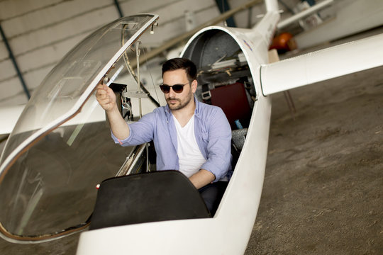 Handsome young pilot checking his ultralight airplane before flight