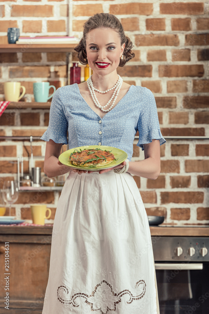 Wall mural happy adult housewife in vintage clothes holding plate with mushroom cake at kitchen