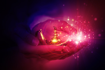 magic lamp of aladdin in female hands on a dark abstract background. Calling the genie to fulfill...