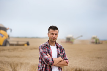 Naklejka na ściany i meble Farmer standing in field during harvest