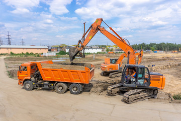 Two excavators load the earth into a dump truck