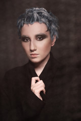 Portrait of girl with short dyed blue hair in eyeglasses on black background. Creative coloring and haircut.
