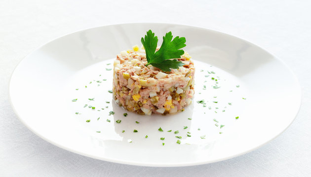 salad of cod liver, onion, egg,  and pickled cucumber decorated with chopped parsley and parsley leaf