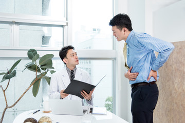 腹痛を訴える男性と診察をする医者