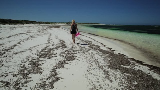 Beach fun summer vacation. Joyful happy woman walking on the seashore of pristine and white sand in Hangover Bay, Nambung National Park, Western Australia. Blonde girl happiness walk. Copy Space.