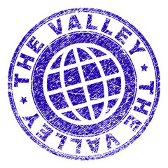 THE VALLEY stamp imprint with distress texture. Blue vector rubber seal imprint of THE VALLEY tag with scratched texture. Seal has words arranged by circle and globe symbol.