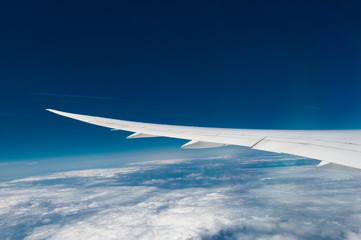 Fototapeta na wymiar Wing of airplane flying above the clouds in the sky