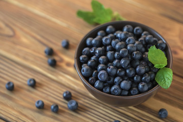 Fresh blueberry in ceramic bowl on wooden table.