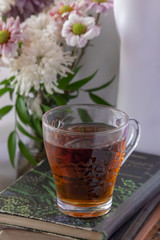 A glass of tea on the book and a vase of flowers