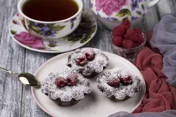 Cake with raspberries and sugar powder on the table with tea teapot.