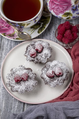 Cake with raspberries and sugar powder on the table with tea teapot.