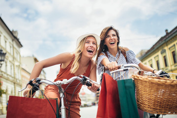 Two beautiful women shopping on bike in the city