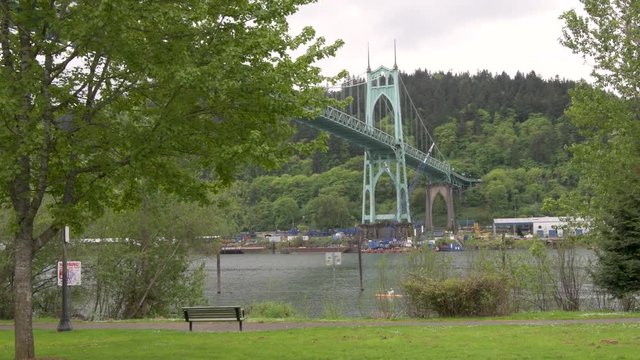 Cathedral Park in Portland, Oregon on an overcast dayView of the St Johns Bridge crossing the Willamette river, framed by trees, from . A kayaker goes by.