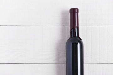 Single Bottle of Wine on a White Wood Table. The thin bottle has a wax seal over the top.