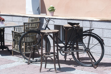 Fototapeta na wymiar Old vintage bicycle as decorative element of city street bistro in sunny summer day