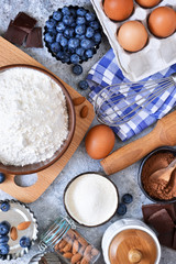 Food background. Ingredients for baking: flour, eggs, berries, chocolate on a concrete background.
