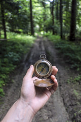 Man with compass in hand in lush summer forest. Travel concept